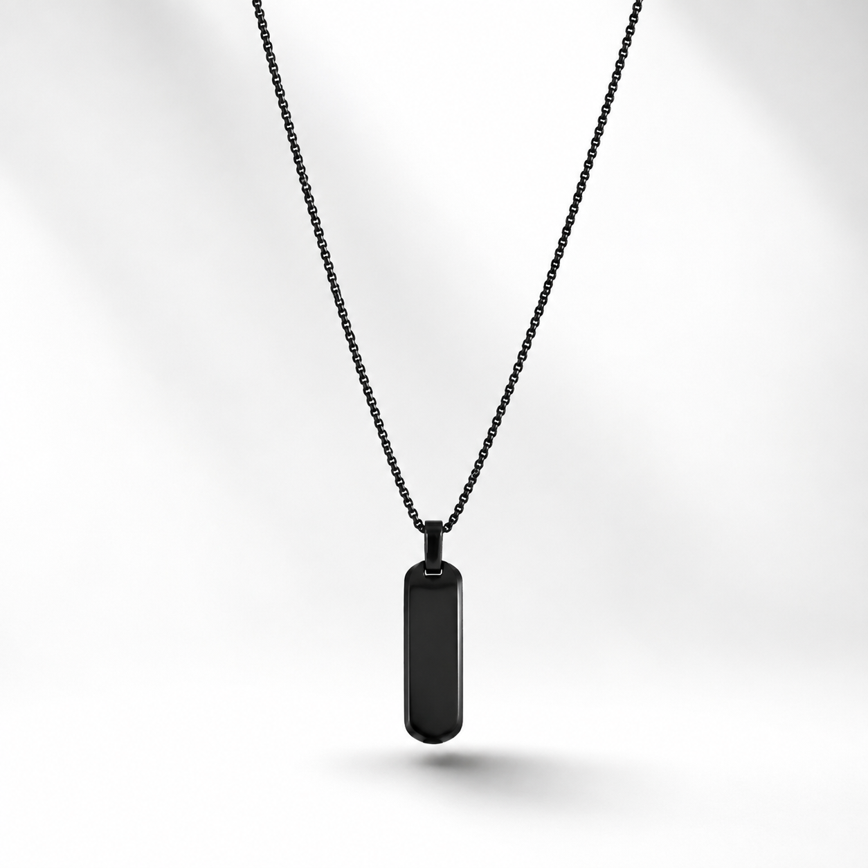 A black rectangular pendant for men necklace with a smooth, glossy finish hanging from a delicate black chain in doha qatar