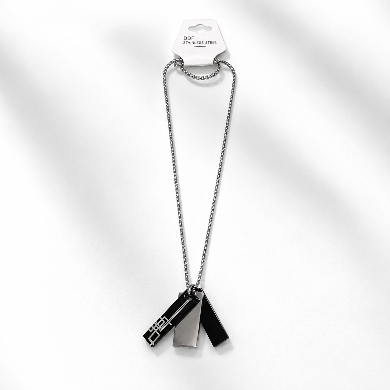 A silver stainless steel chain necklace with three geometric pendant charms